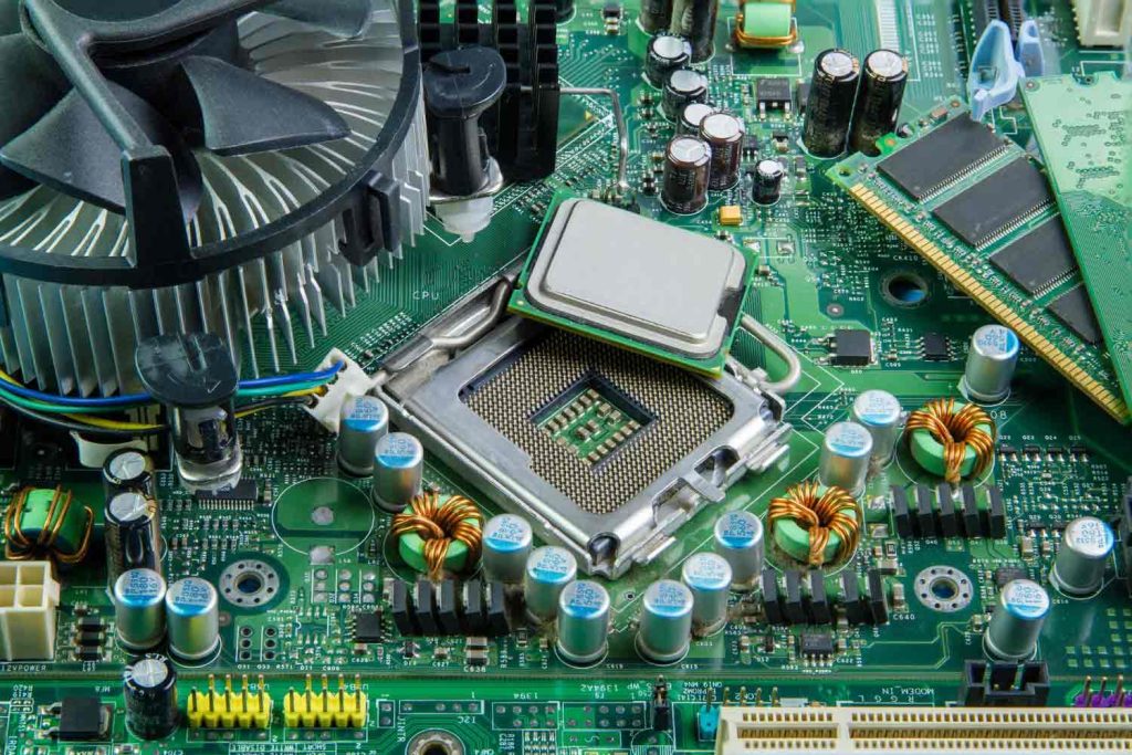 Desktop motherboard with a CPU partially lifted from its socket next to RAM modules, showcasing ESDM hardware components.