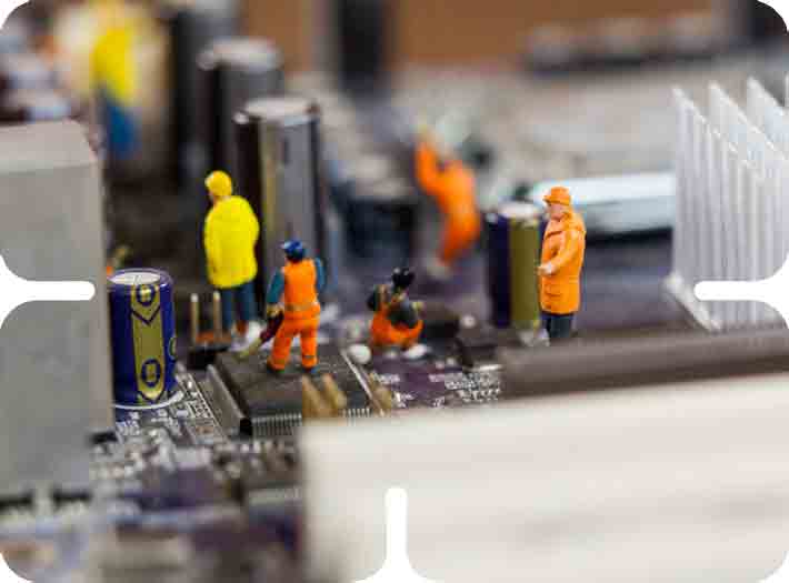 Miniature construction worker figurines performing motherboard hardware repairs and process optimization.